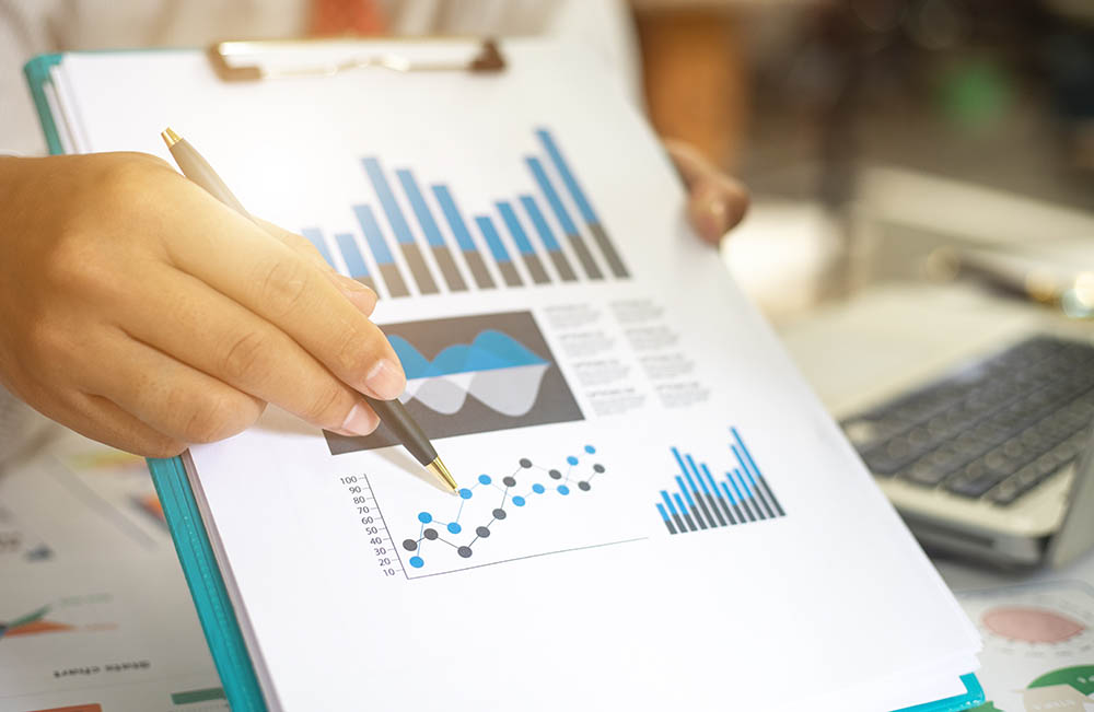 Hand holding pen pointing out statistic diagrams